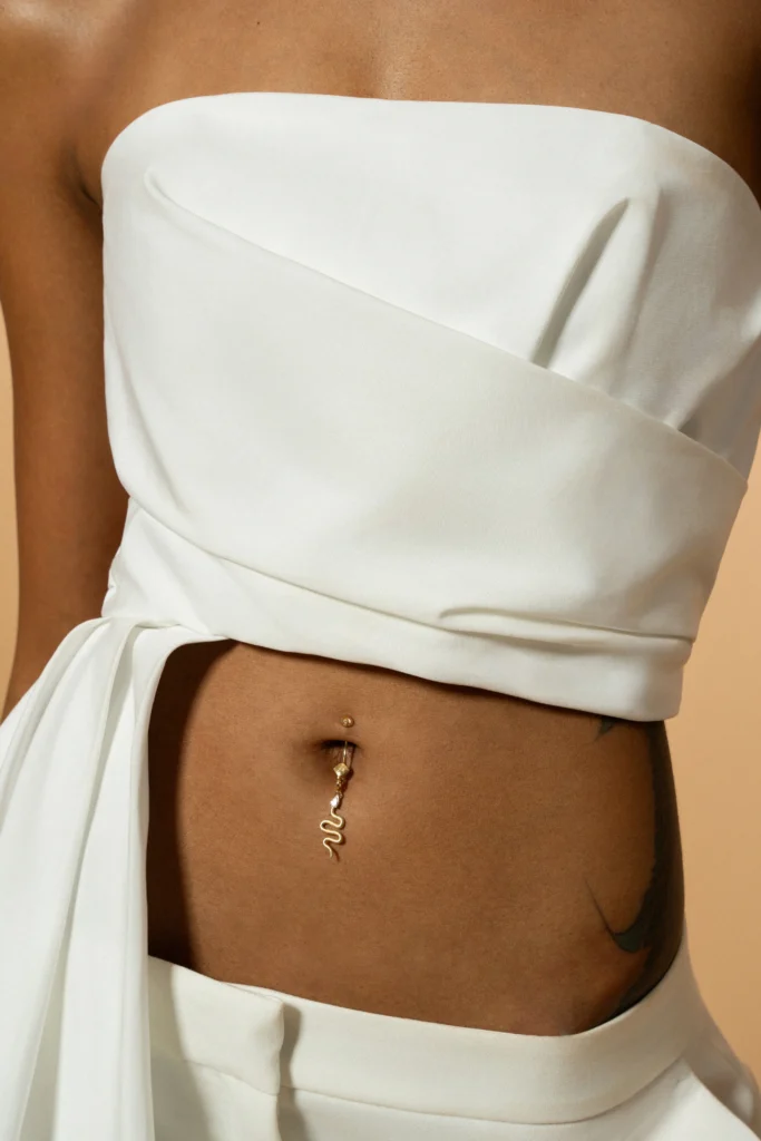 Piercing ombelicale Desiderio Siklah a serpente in oro indossato su modella in abito bianco