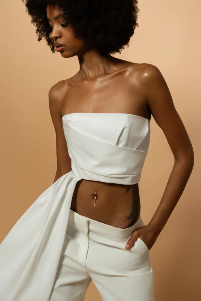 Piercing base Siklah con charm Desiderio a serpente in oro, indossato sull'ombelico, modella in total white