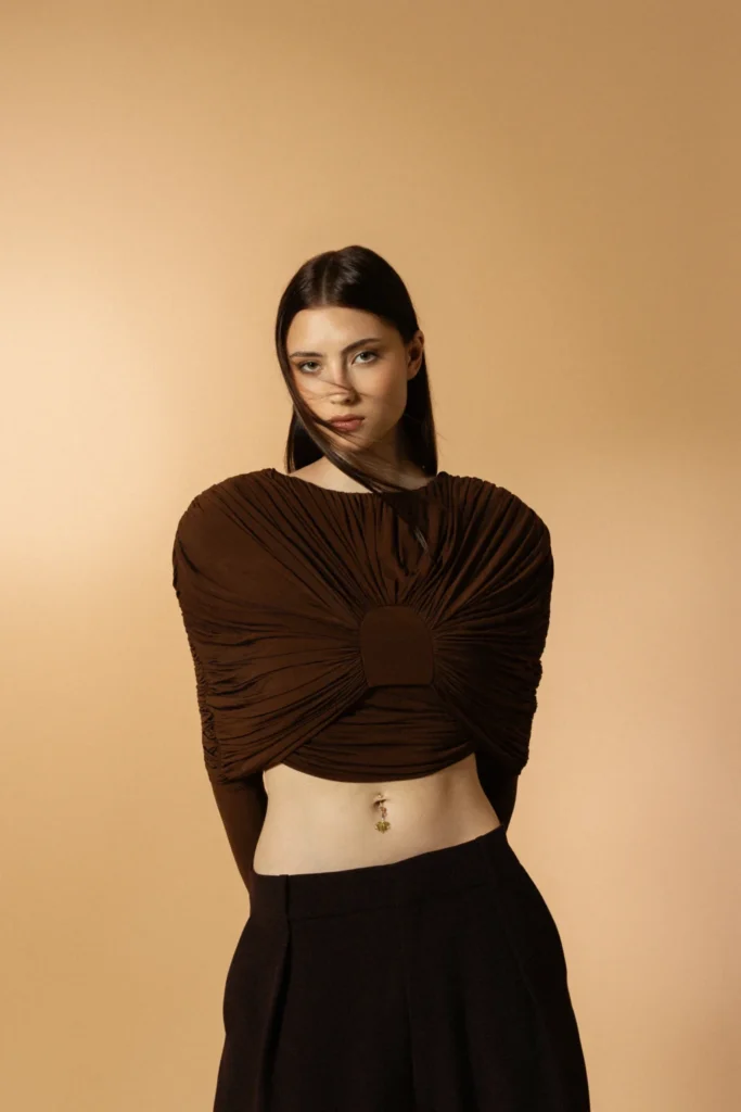 Charm Incanto Siklah al piercing, modella con top marrone plissettato su sfondo beige.