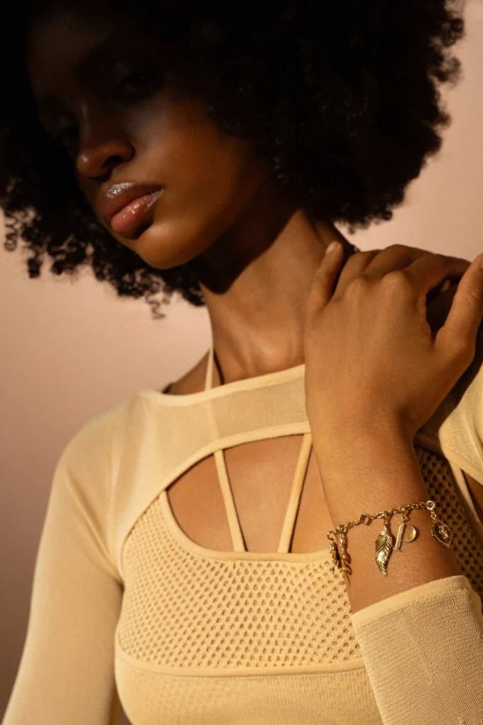 Dettaglio ravvicinato del bracciale Siklah in oro giallo con charm a foglia e iniziale