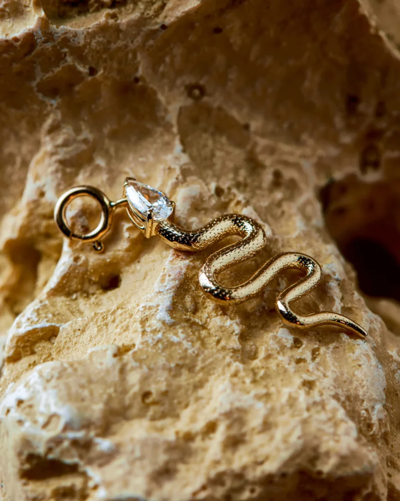 Primo piano del charm serpente Desiderio Siklah in oro con pietra taglio pera, su roccia