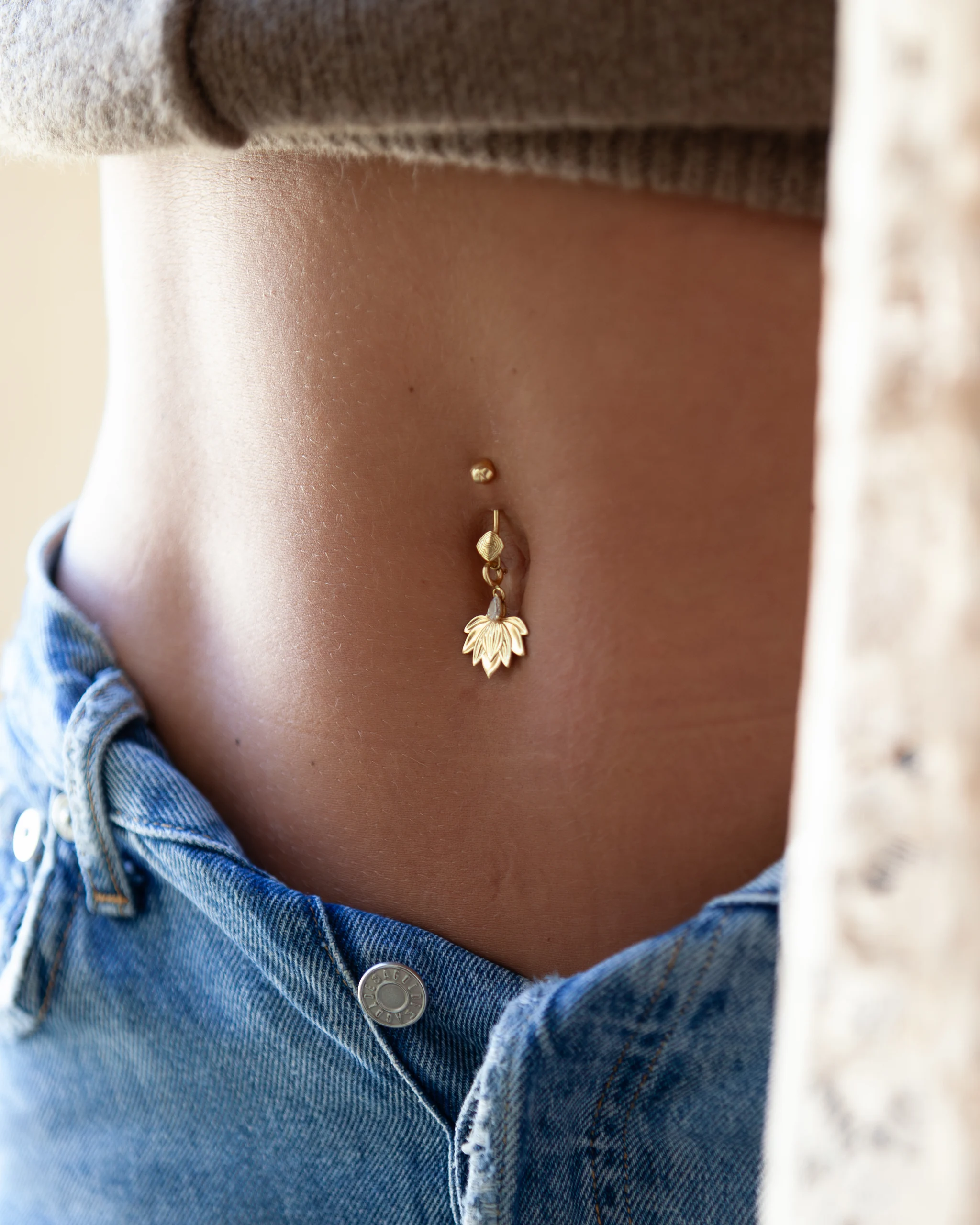 Piercing Base Siklah in oro indossato all'ombelico, con charm a fiore di loto