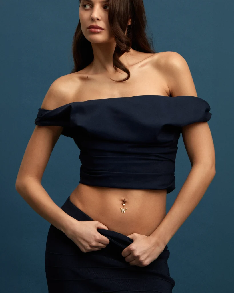 Charm Sogno Siklah in oro giallo a farfalla, indossato su modella in top blu notte